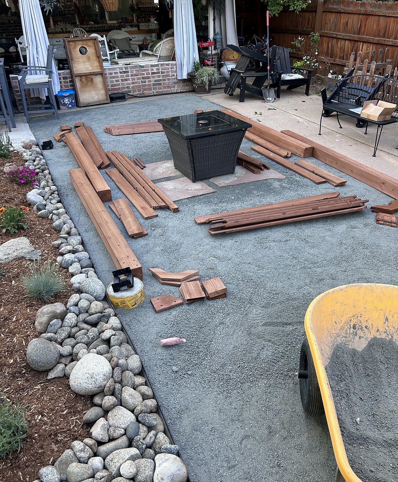 Prepared base with cedar pergola members cut and staged, river rock border in place