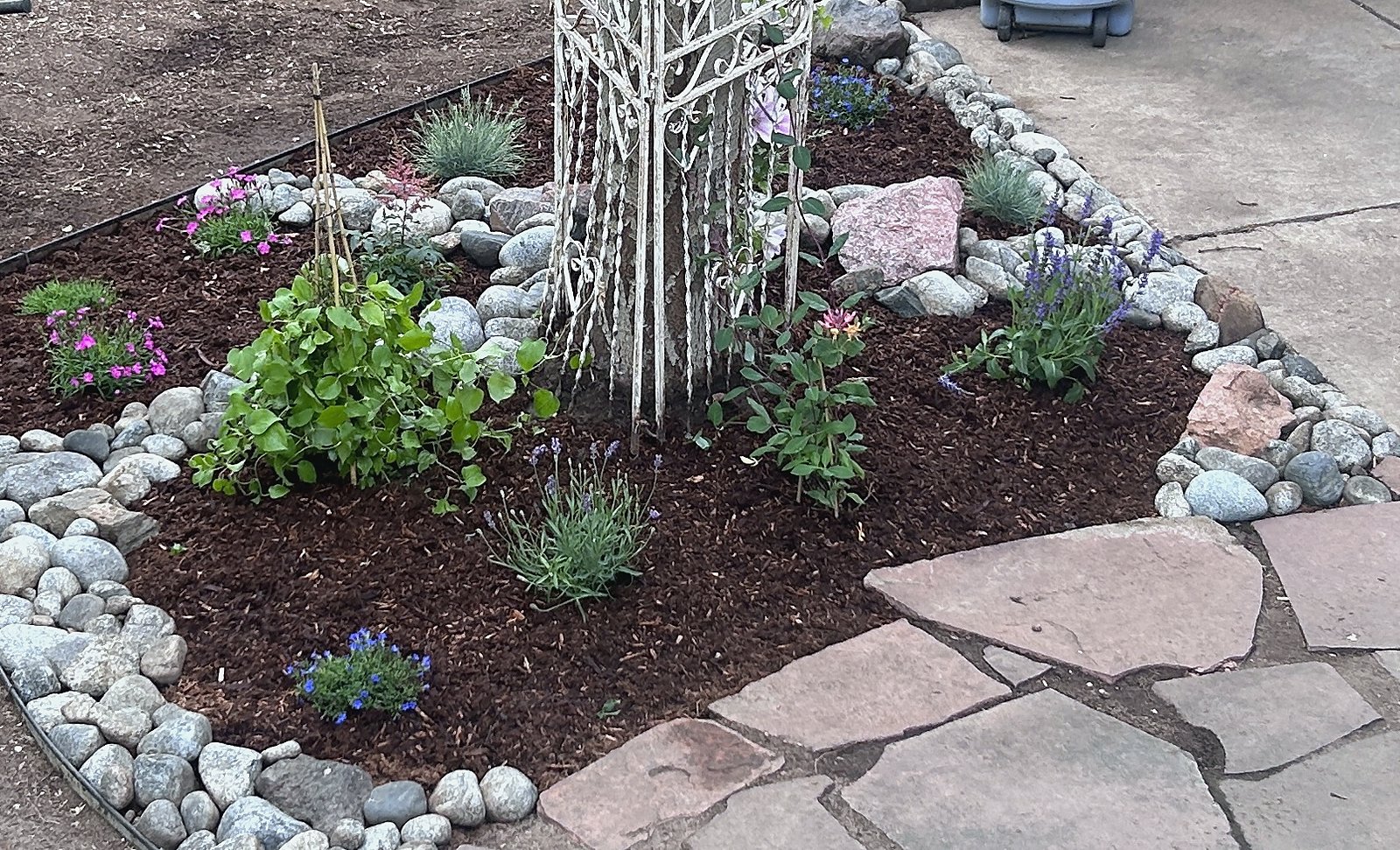 Planting bed edged in river rock cobble against flagstone paving